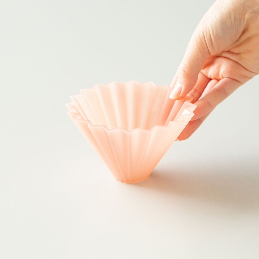 Pink Comandante Origami Air S plastic coffee grinder with a compact design and ergonomic handle for precise grinding.